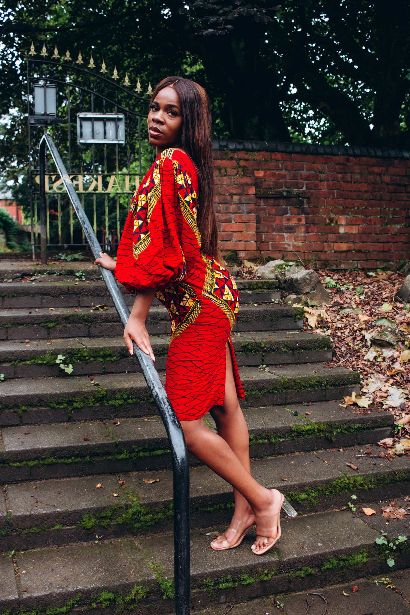Ankara wax print African geo-shaped Triangle pattern in red, yellow and black on long three quarter ballooned sleeves, closed neckline, knee high body hugging pencil dress with belt feature.
