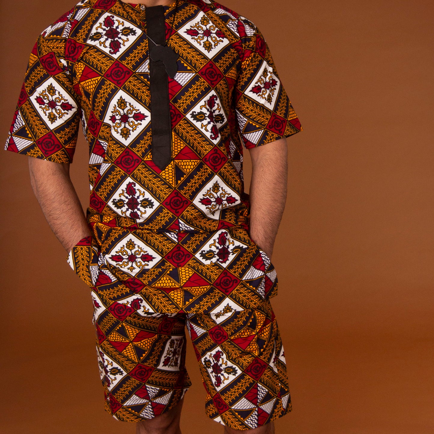 African print kaftan top with black crepe trim and matching shorts with drawstring waist hand-made from red, yellow, white and black ankara wax print in a geometric pattern