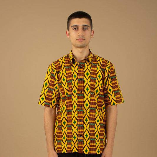 The Adina Kente African printed Button-Up shirt is a striking Diamond geometric kente pattern in  green, yellow and black made from sustainably sourced 100% Cotton. Designed in England Made in Nigeria.