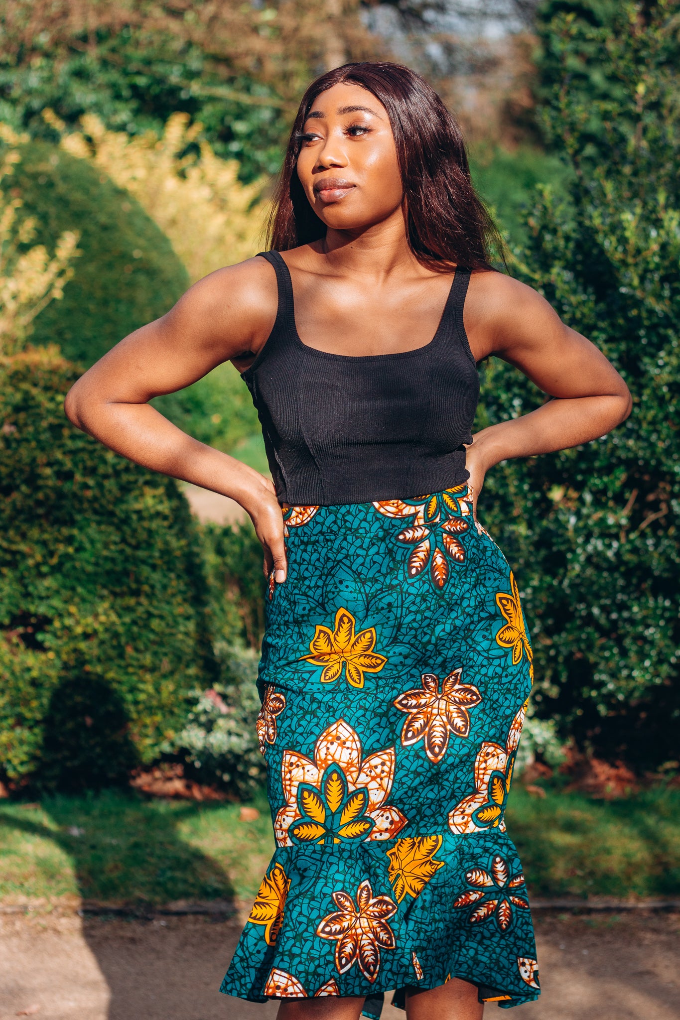 Orange, yellow, white and green African print High Waisted knee length Flared fishtail Skirt with seamed belt detailing in a floral pattern, made from sustainably sourced Ankara wax print.