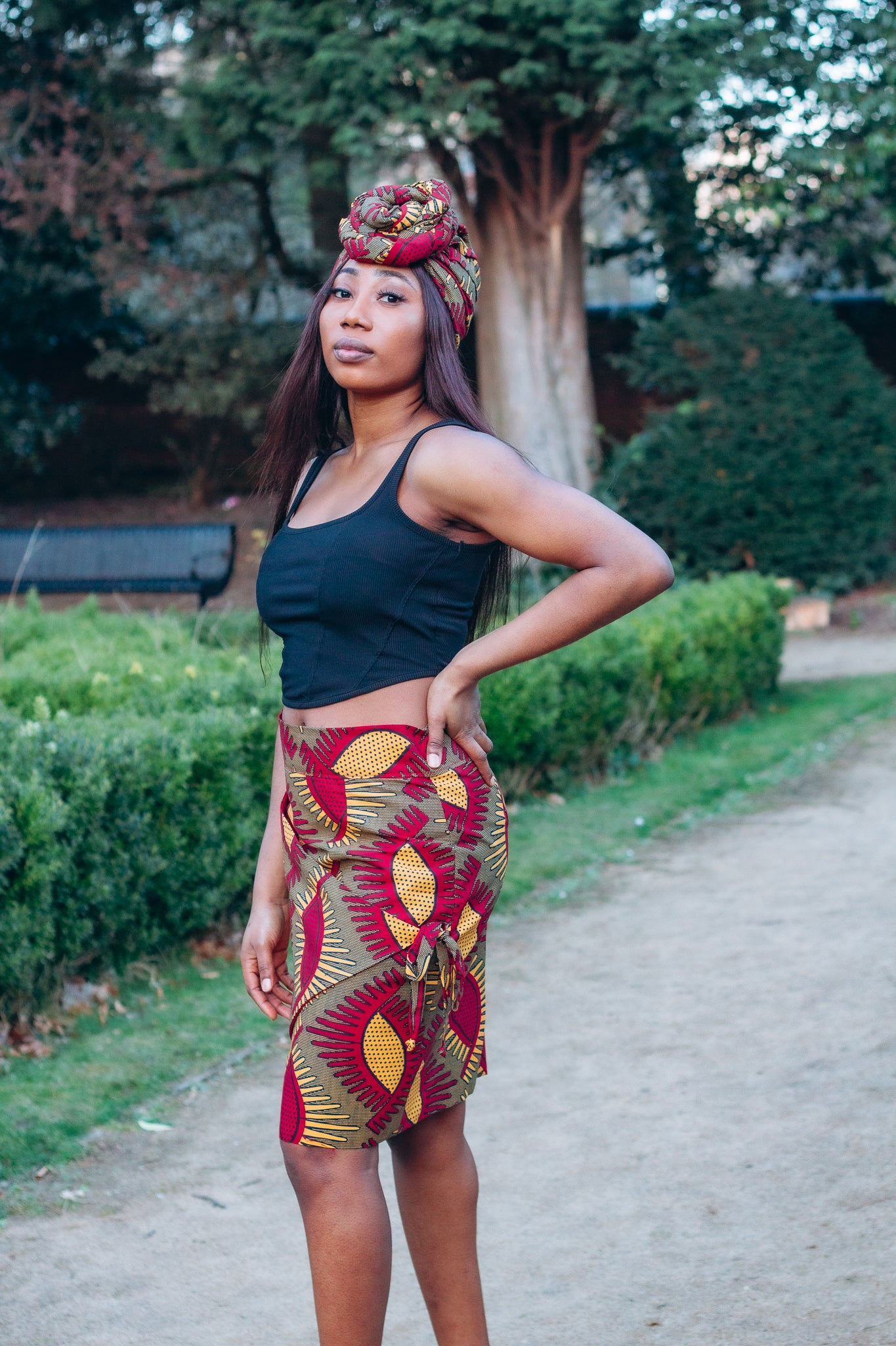 Red, yellow and brown African print head wrap tied a turban in graphic floral pattern, made from sustainably sourced Ankara wax print.