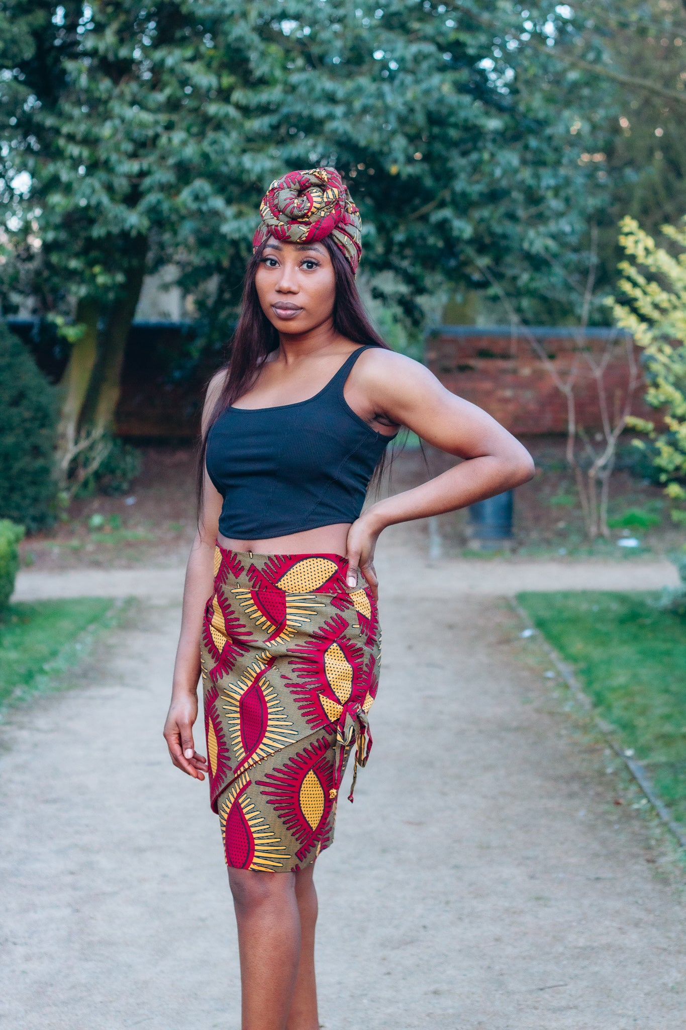 Red, yellow and brown African print head wrap tied a turban in graphic floral pattern, made from sustainably sourced Ankara wax print.