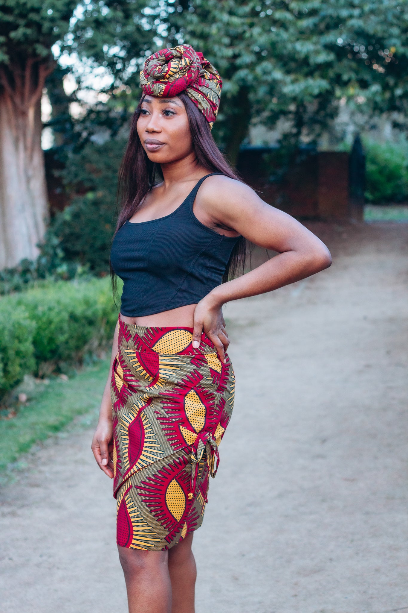 Red, yellow and brown African print head wrap tied a turban in graphic floral pattern, made from sustainably sourced Ankara wax print.