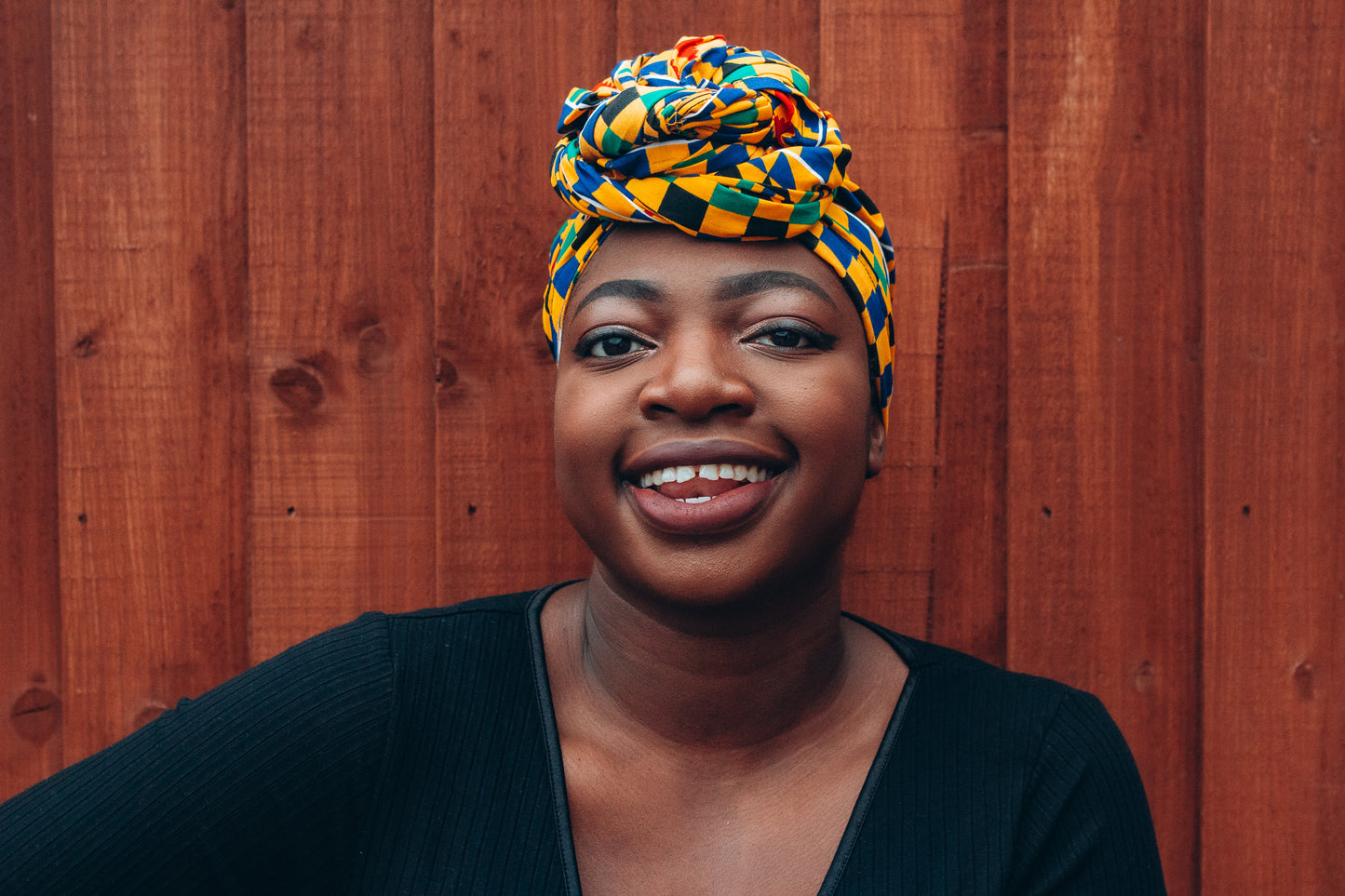 Yellow, green, blue, red and black African print head wrap tied as turban in a checkered pattern, made from sustainably sourced Ankara wax print.