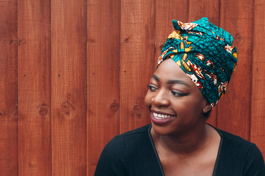 Orange, yellow, white and green African print head wrap tied a turban in a floral pattern, made from sustainably sourced Ankara wax print.