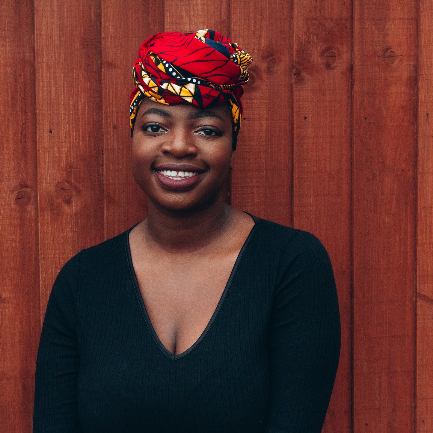 red, yellow, white, and black African print head wrap tied as a turban in a graphic pattern, made from sustainably sourced Ankara wax print.