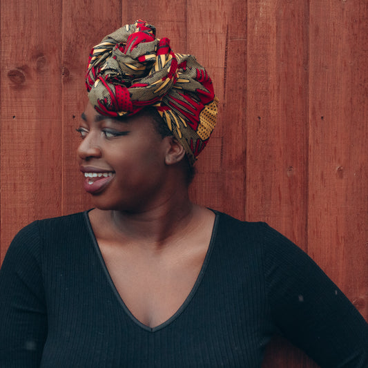 Brown, red and yellow African print head wrap tied a turban in textured pattern, made from sustainably sourced Ankara wax print.