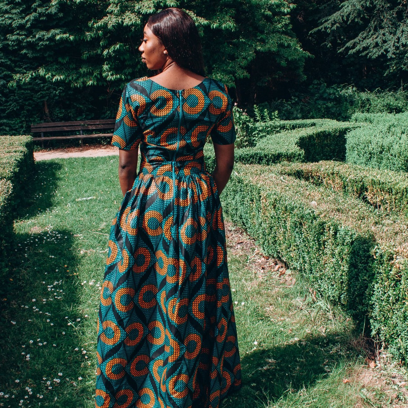 Orange, green and black African printed floor length high to low maxi skirt with a thigh high slit with ruffle detailed and seamed belt in a circle geo-shaped pattern, made from sustainably sourced Ankara wax print.