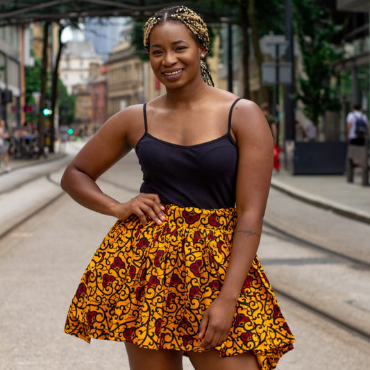 Yellow, red and black African print knee length pleated skater skirt in floral pattern, made from sustainably sourced Ankara wax print with belted seam detail.