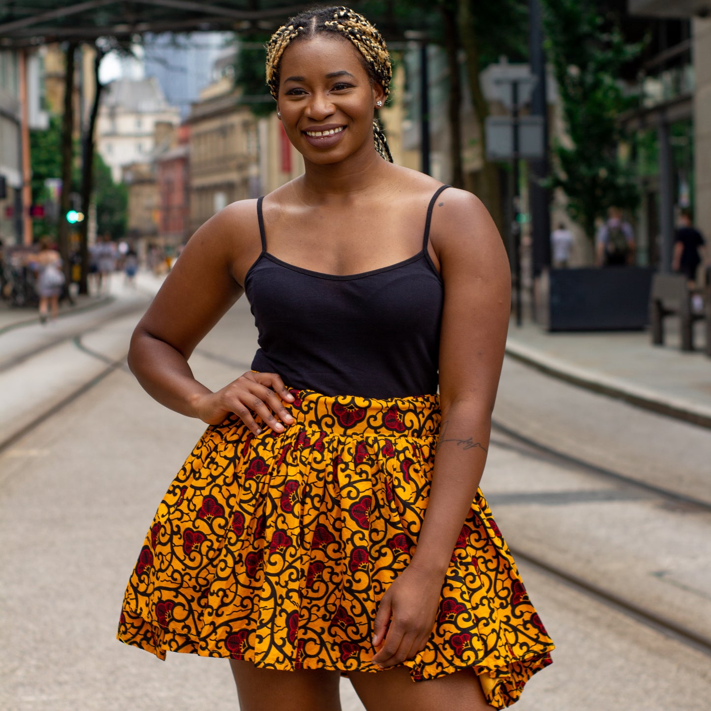 Yellow, red and black African print knee length pleated skater skirt in floral pattern, made from sustainably sourced Ankara wax print with belted seam detail.