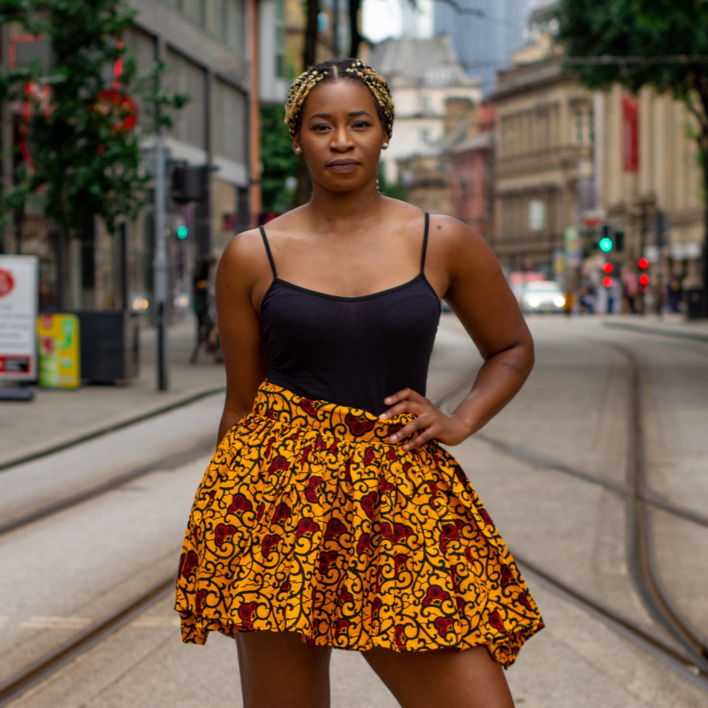 Yellow, red and black African print knee length pleated skater skirt in floral pattern, made from sustainably sourced Ankara wax print with belted seam detail.