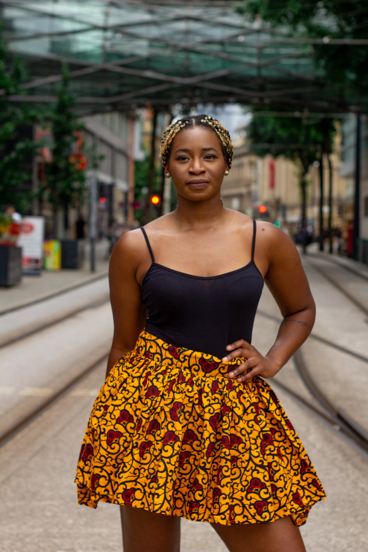 Yellow, red and black African print knee length pleated skater skirt in floral pattern, made from sustainably sourced Ankara wax print with belted seam detail.