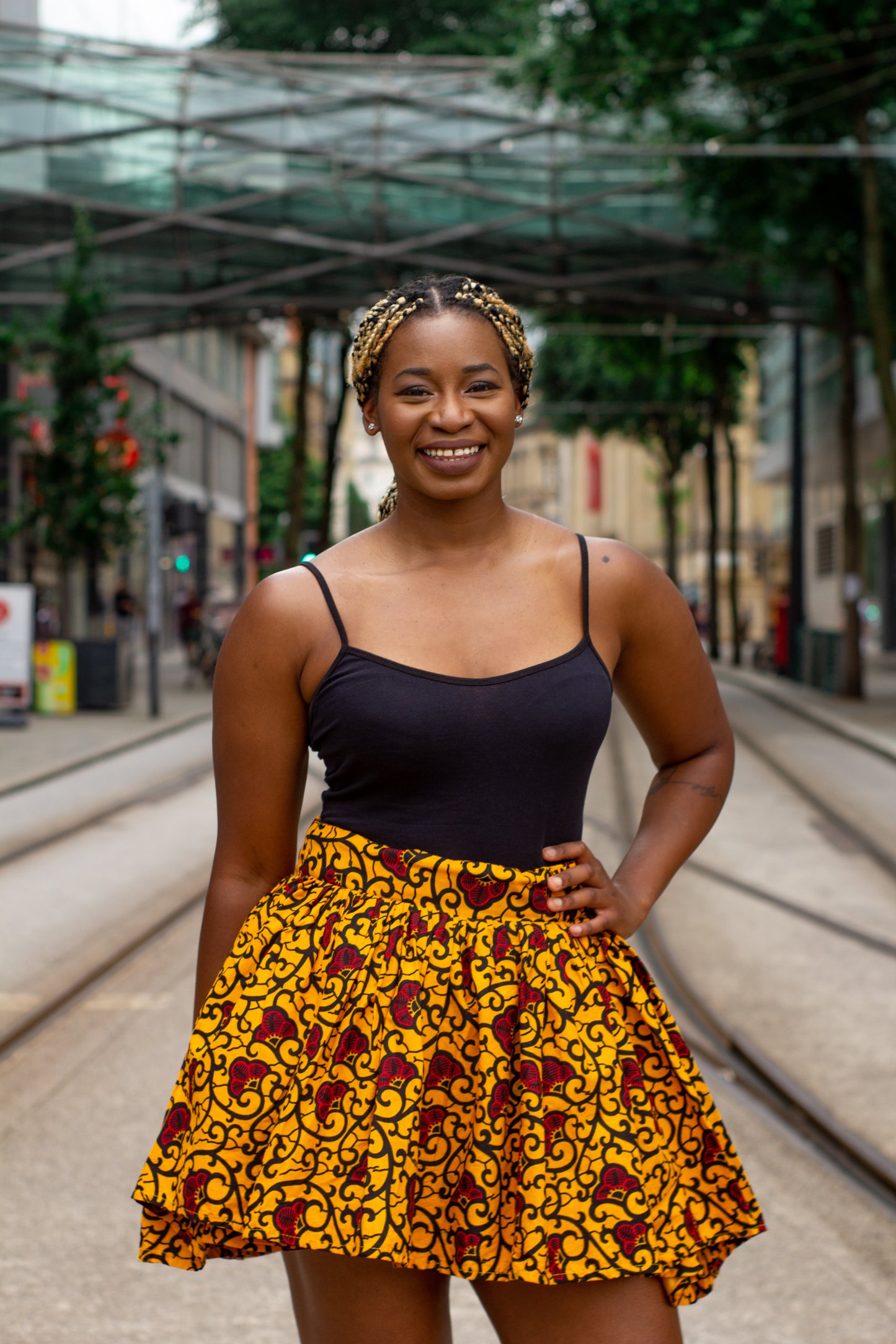 Yellow, red and black African print knee length pleated skater skirt in floral pattern, made from sustainably sourced Ankara wax print with belted seam detail.