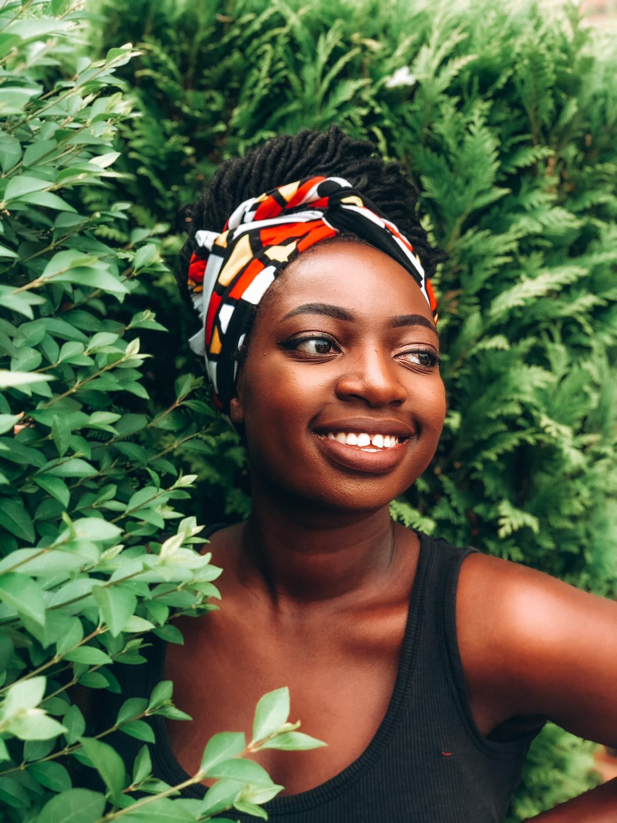 Red, pastel yellow, white and black African print head wrap tied as a turban, in oversized geo-shaped pattern made from sustainably sourced Ankara wax print.