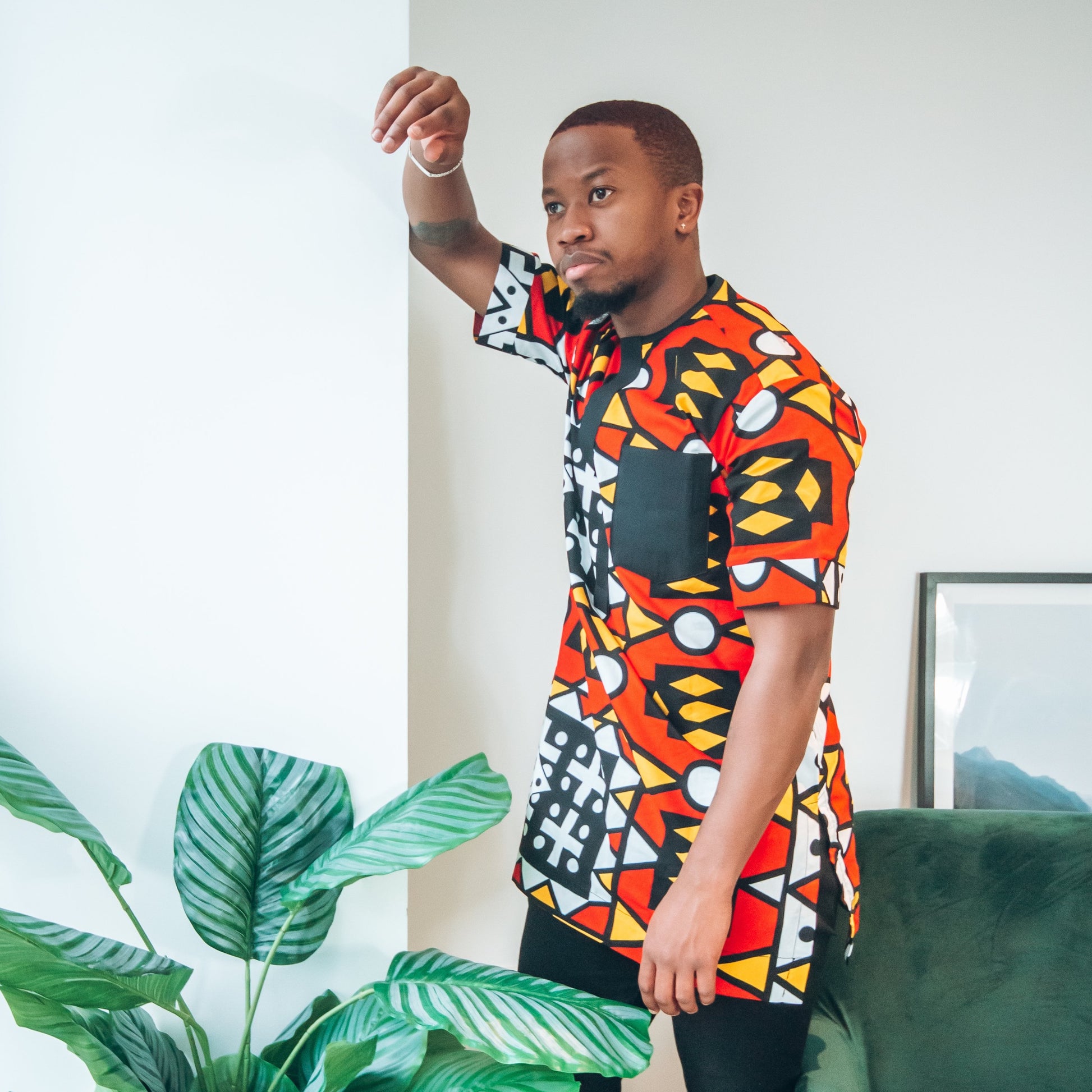 Black man in an African print red, white and yellow top