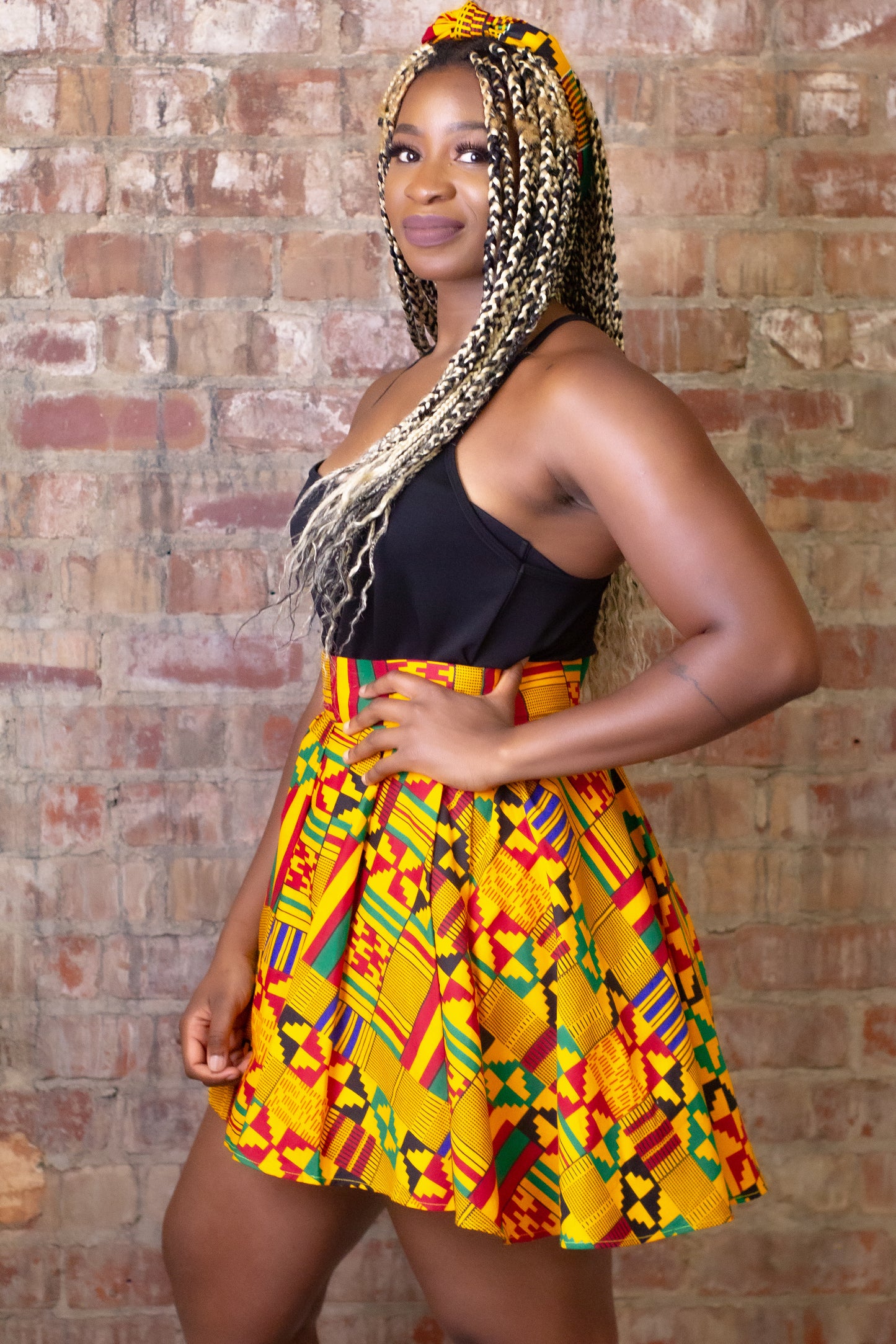 ellow, green, red, and black African print head wrap tied as headband in a geo-shaped pattern, made from sustainably sourced Ankara wax print.