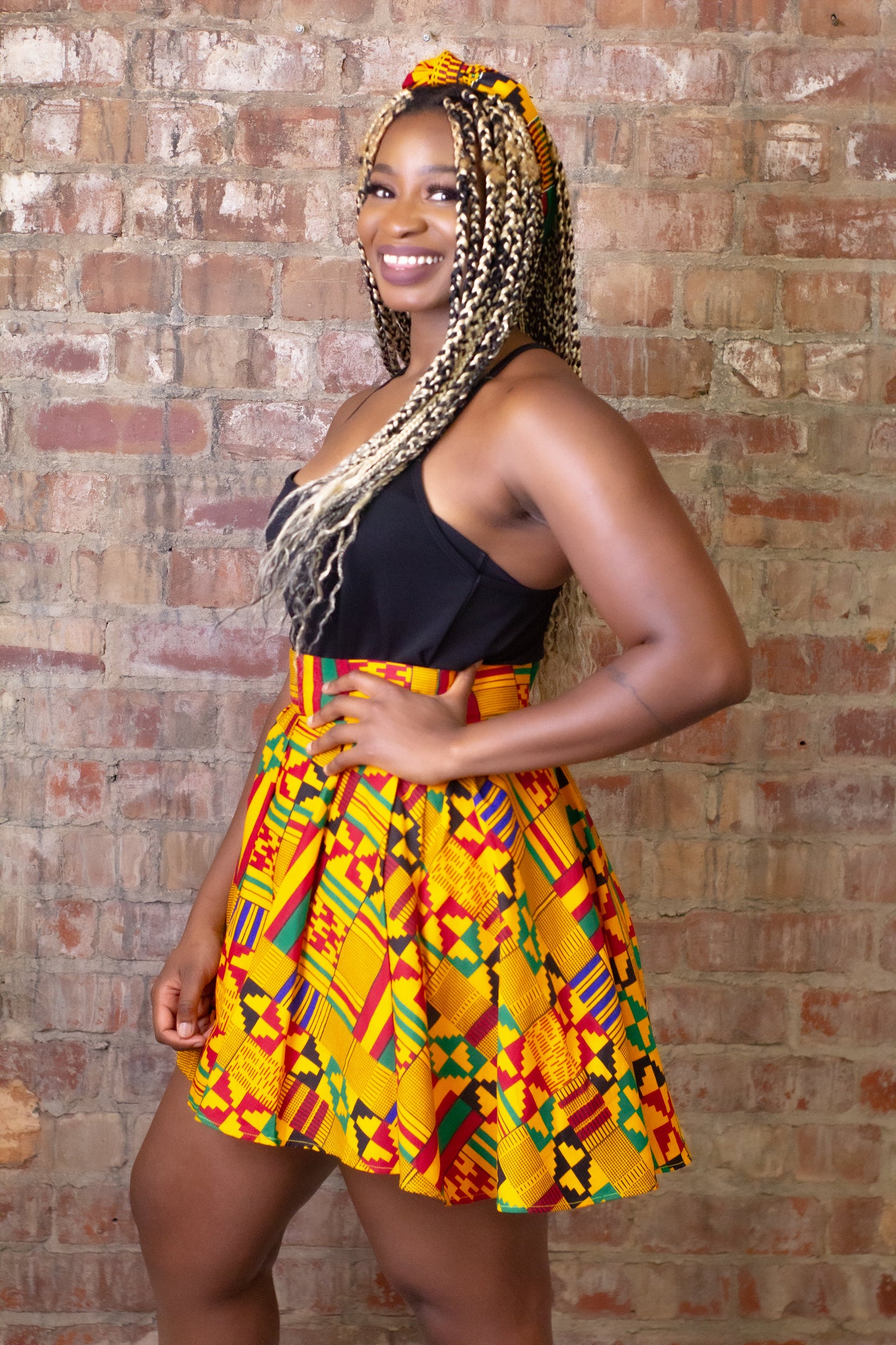 ellow, green, red, and black African print head wrap tied as headband in a geo-shaped pattern, made from sustainably sourced Ankara wax print.