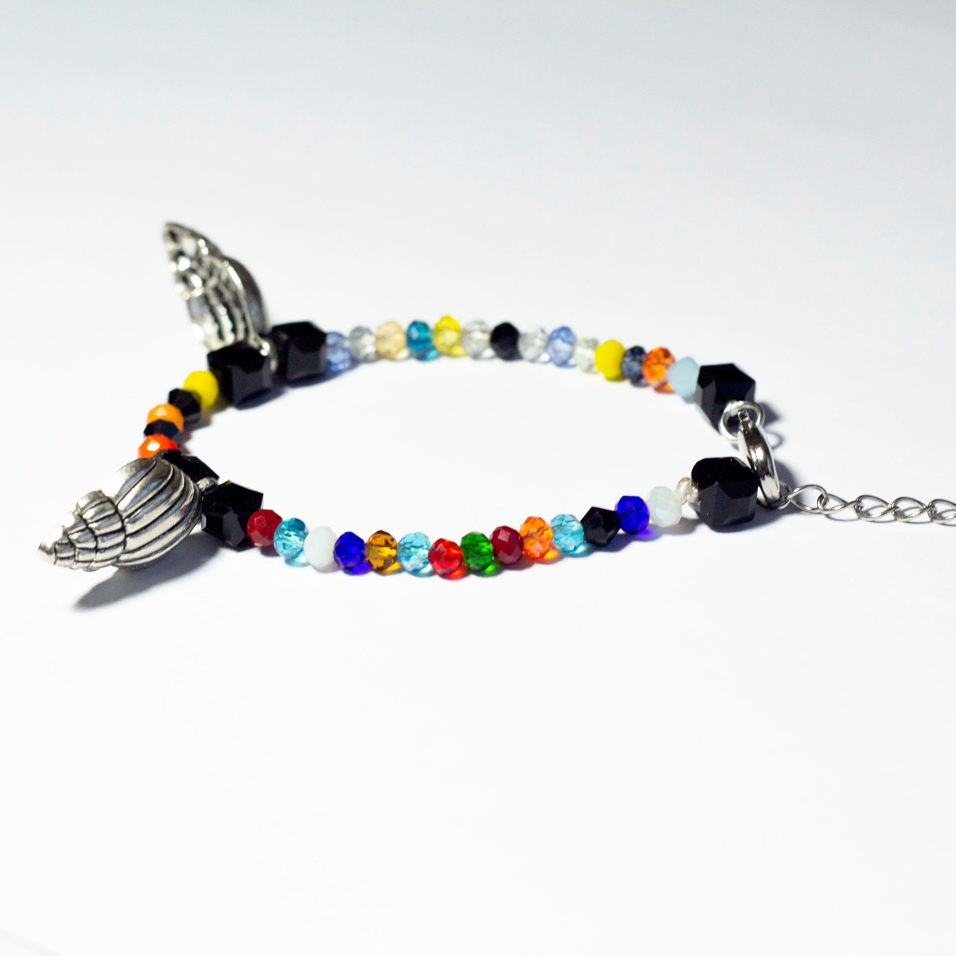 Multicoloured beaded bracelet made of crystal beads featuring metallic seashell pendants and a chain clasp design