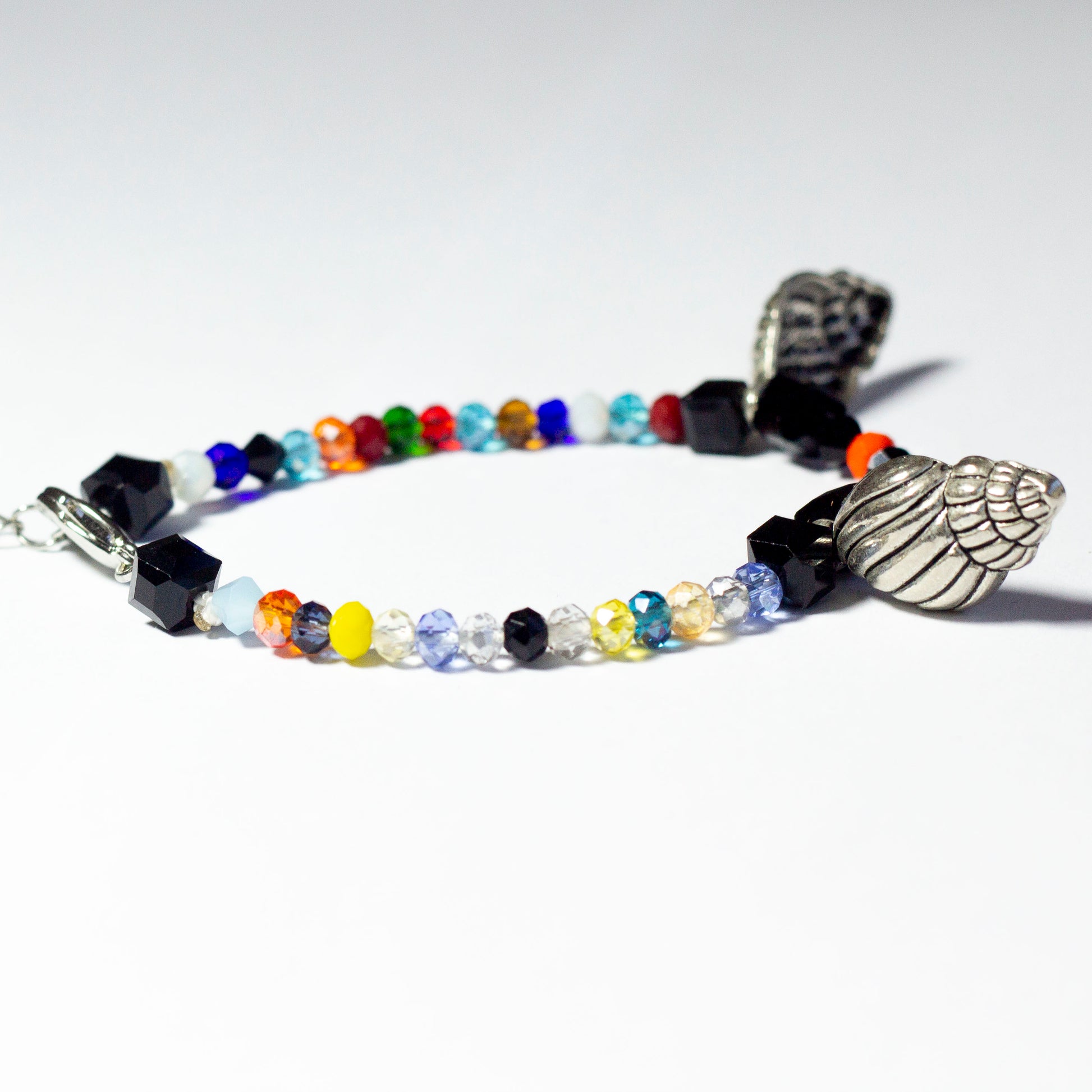 Multicoloured beaded bracelet made of crystal beads featuring metallic seashell pendants and a chain clasp design