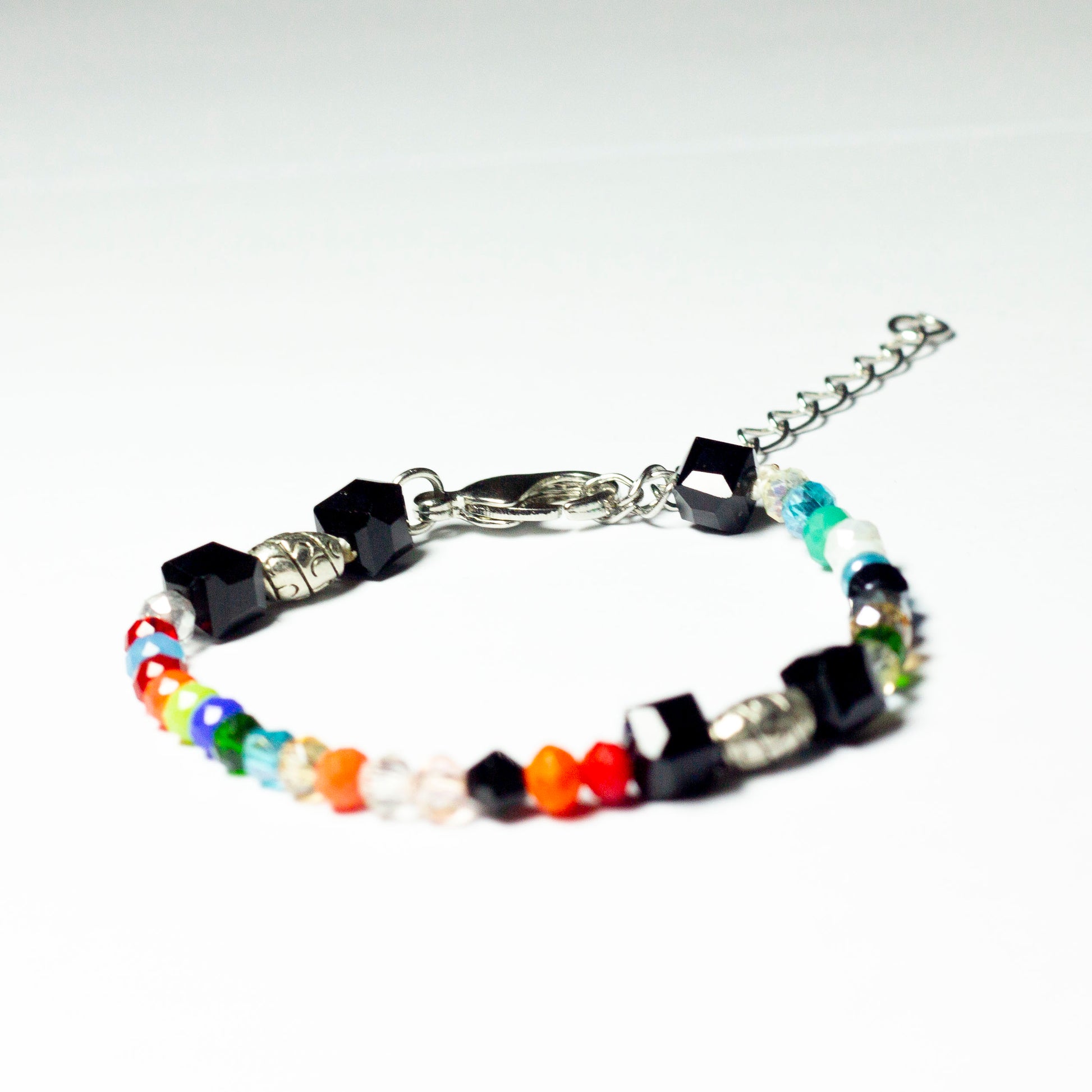 Multicoloured beaded bracelet made of crystal beads featuring engraved cylinder pendants and a chain clasp design