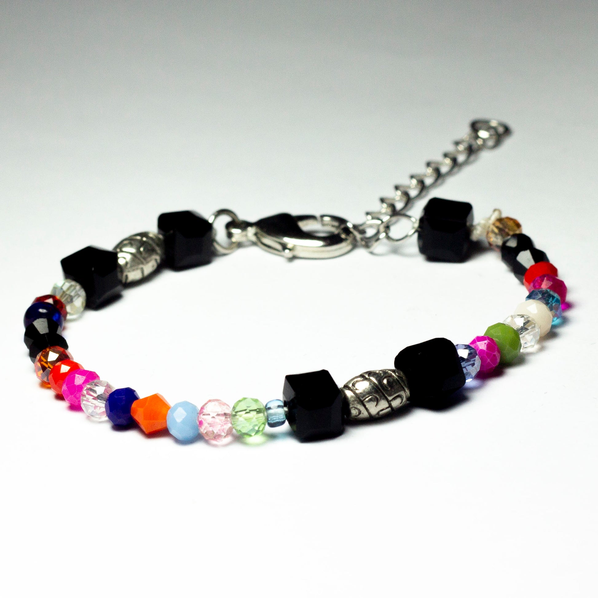 Multicoloured beaded bracelet made of crystal beads featuring engraved cylinder pendants and a chain clasp design