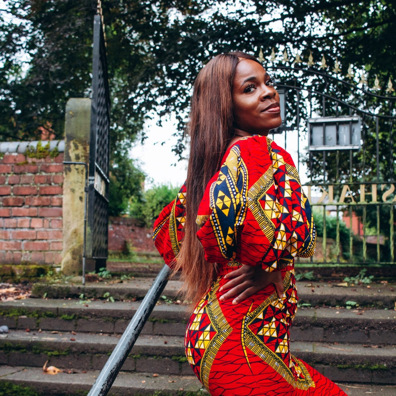 Ankara wax print African geo-shaped Triangle  pattern in red, yellow and black on long  three quarter ballooned sleeves, closed neckline, knee high body hugging pencil dress with belt feature.