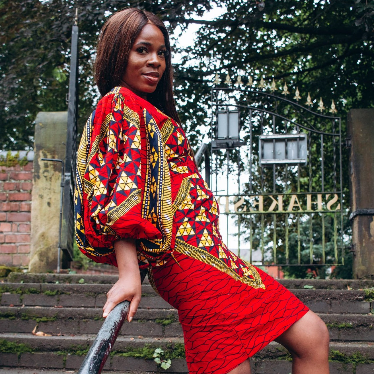 Ankara wax print African geo-shaped Triangle  pattern in red, yellow and black on long  three quarter ballooned sleeves, closed neckline, knee high body hugging pencil dress with belt feature.
