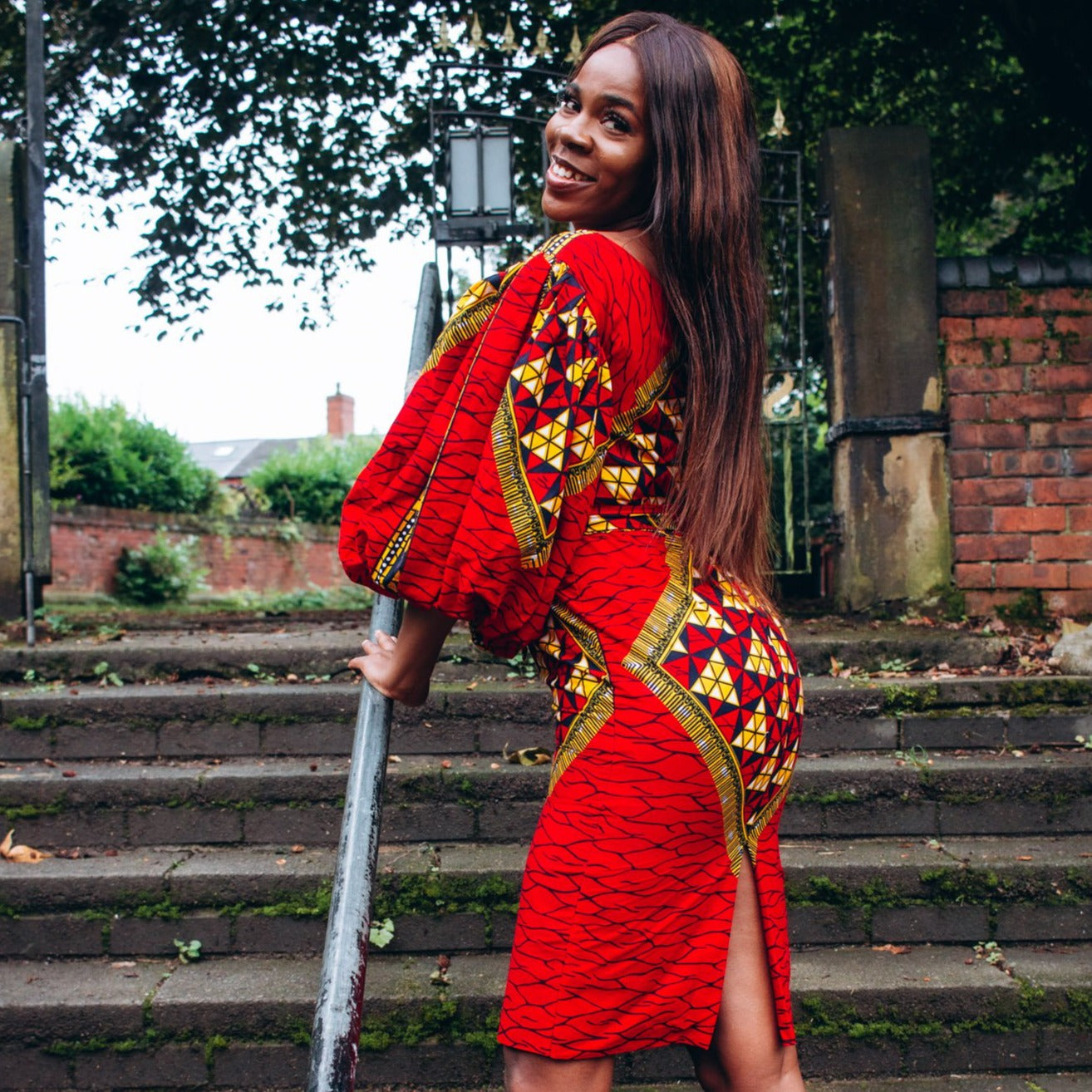 Ankara wax print African geo-shaped Triangle  pattern in red, yellow and black on long  three quarter ballooned sleeves, closed neckline, knee high body hugging pencil dress with belt feature.