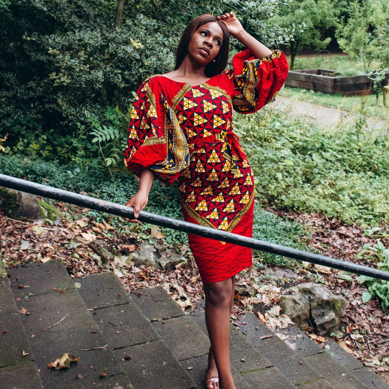 Ankara wax print African geo-shaped Triangle  pattern in red, yellow and black on long  three quarter ballooned sleeves, closed neckline, knee high body hugging pencil dress with belt feature.