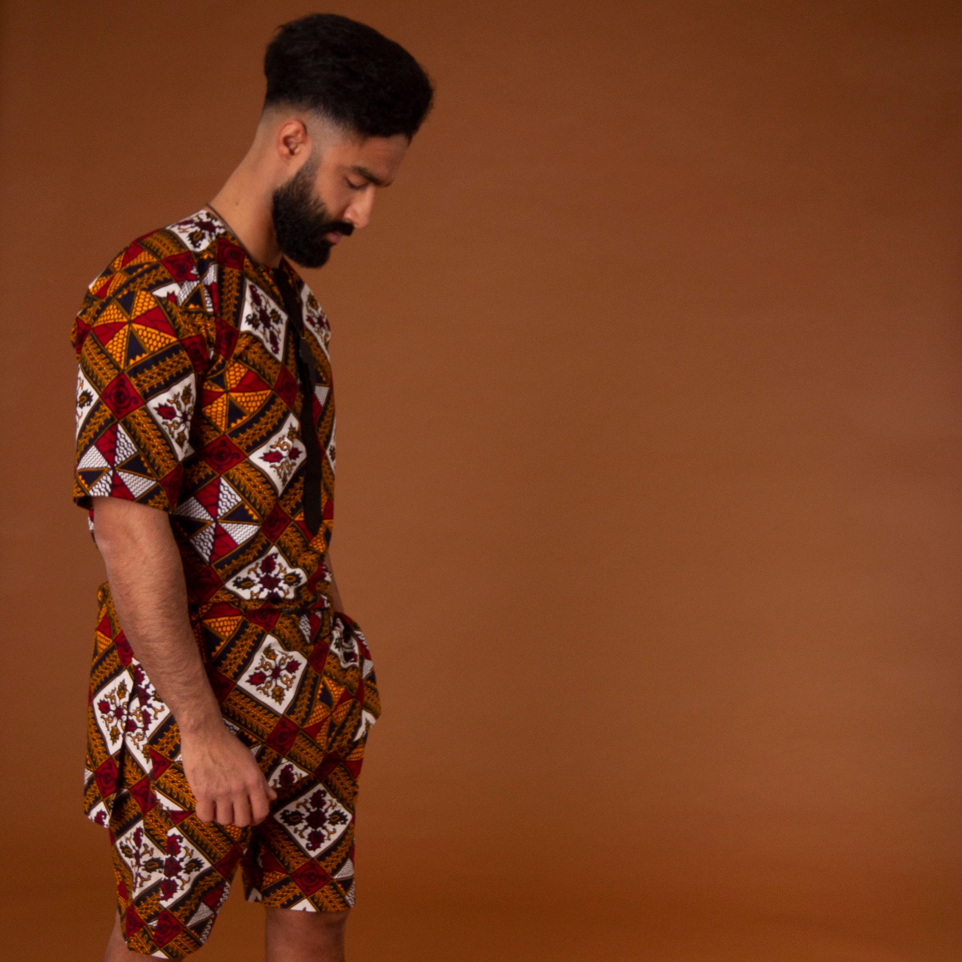 African print kaftan top with black crepe trim on the neckline hand-made from red, yellow, white and black ankara wax print in a geometric pattern