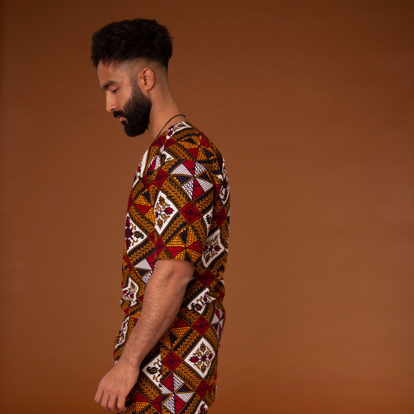 African print kaftan top with black crepe trim on the neckline hand-made from red, yellow, white and black ankara wax print in a geometric pattern