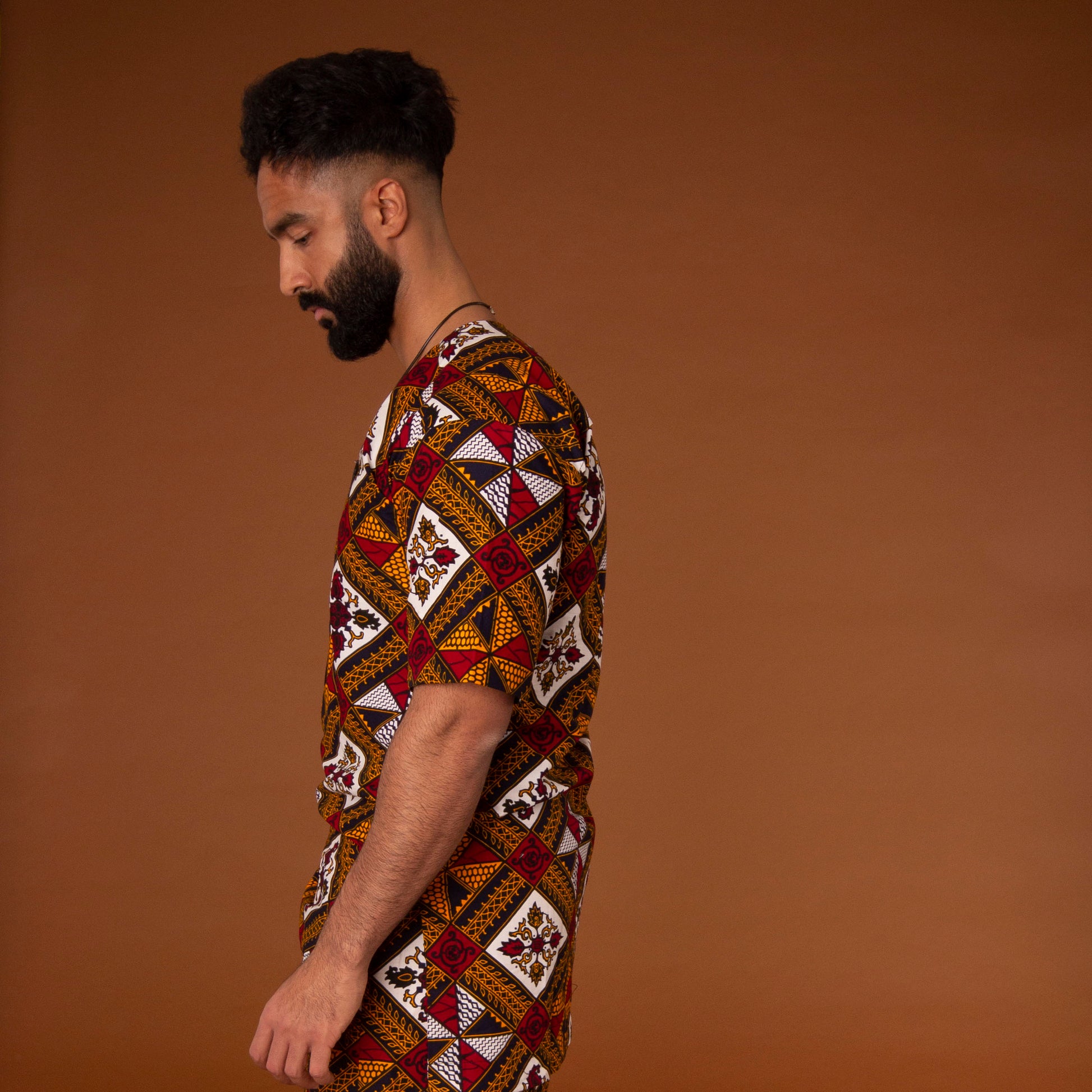 African print kaftan top with black crepe trim on the neckline hand-made from red, yellow, white and black ankara wax print in a geometric pattern