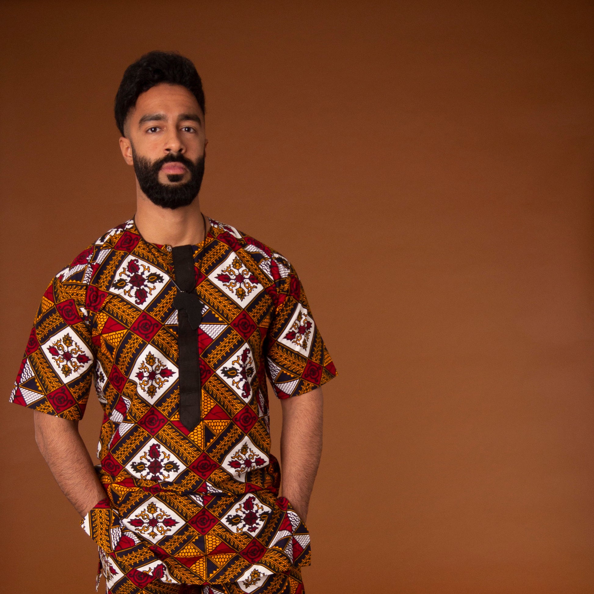 African print kaftan top with black crepe trim on the neckline hand-made from red, yellow, white and black ankara wax print in a geometric pattern