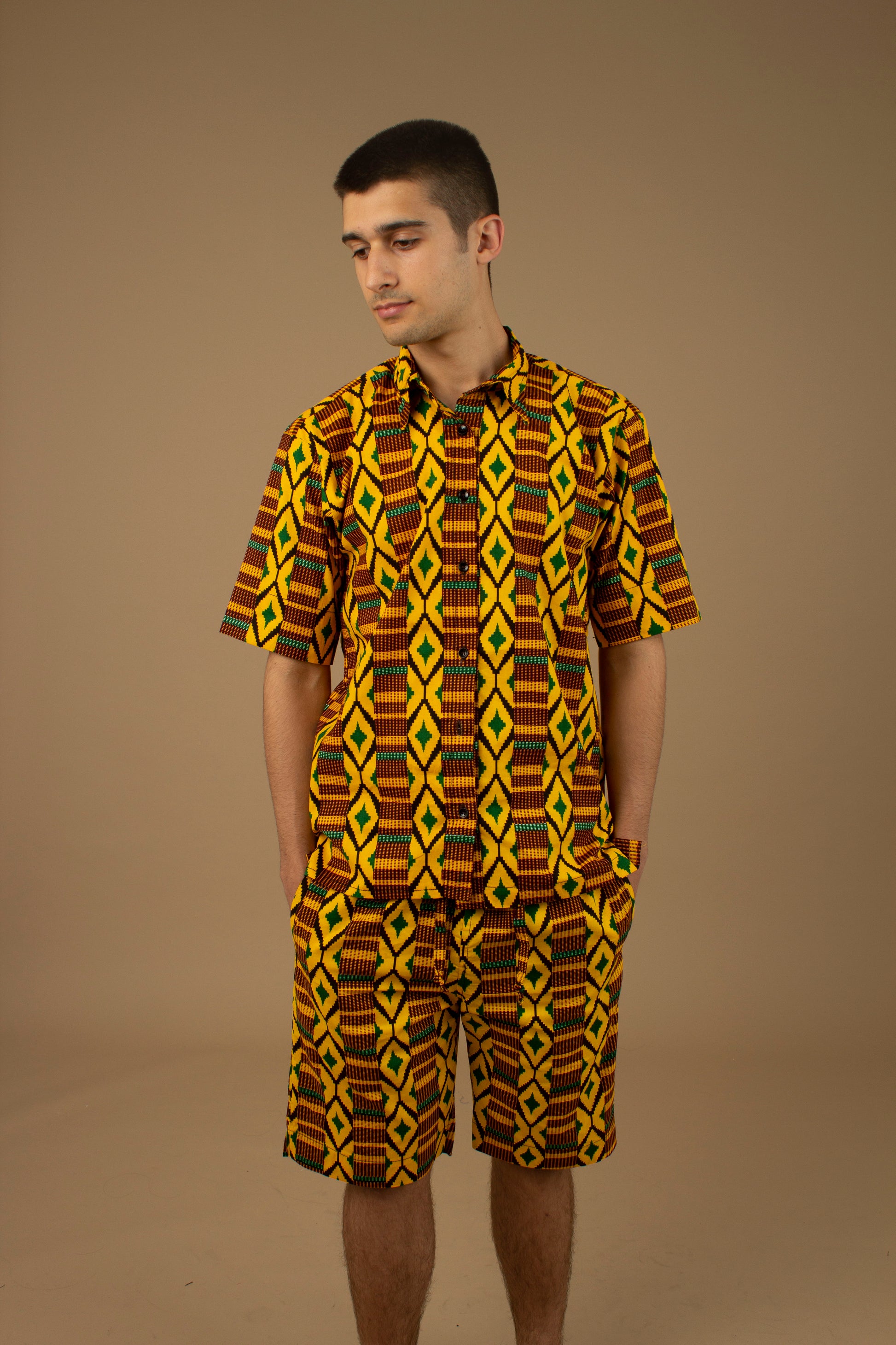 The Adina Kente African Print two- piece Button-Up shirt and Shorts in a striking Diamond geometric kente pattern in  green, yellow and black made from sustainably sourced 100% Cotton. Designed in England Made in Nigeria.