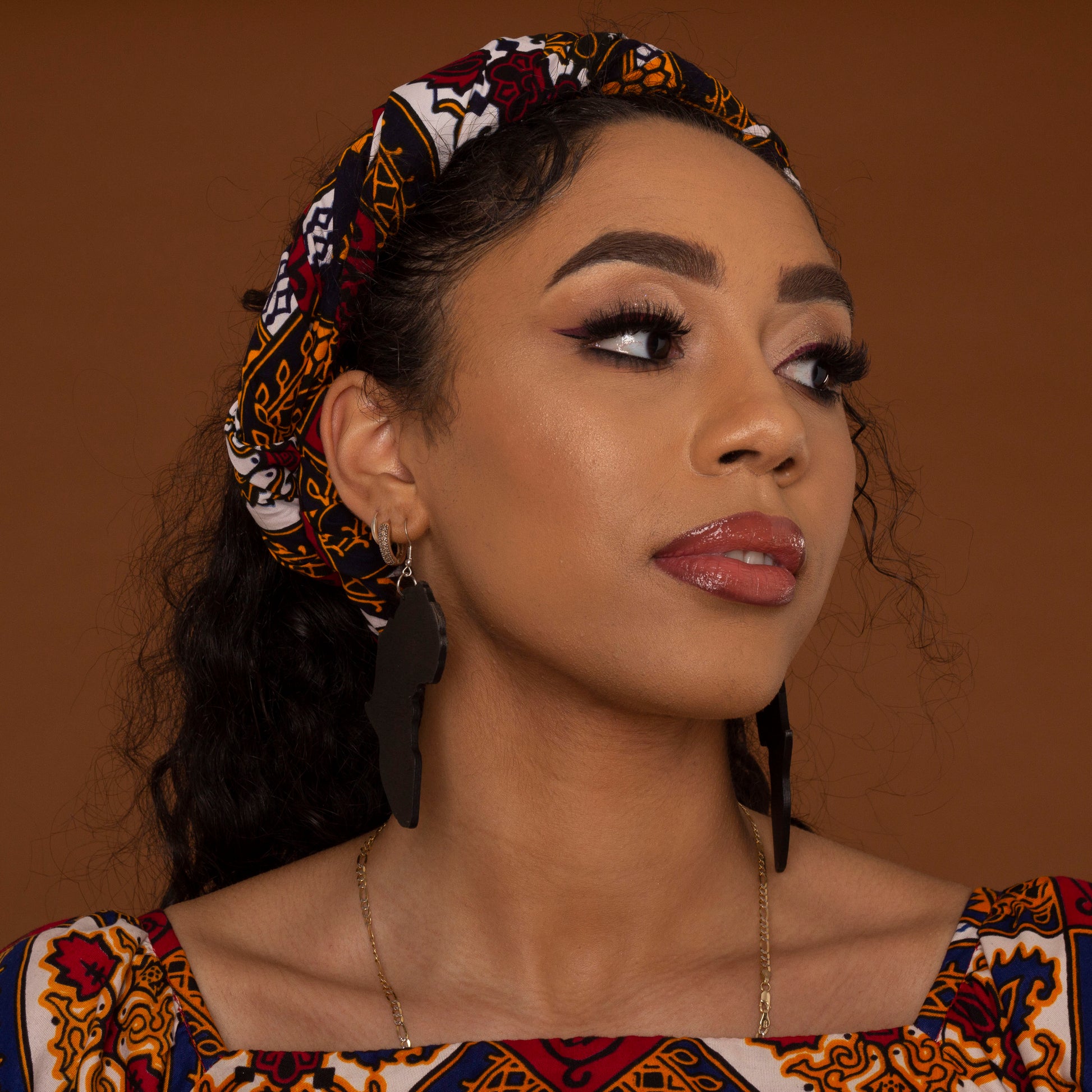 red, yellow, white, and black African print head wrap tied as a turban in floral medallion pattern, made from sustainably sourced Ankara wax print.