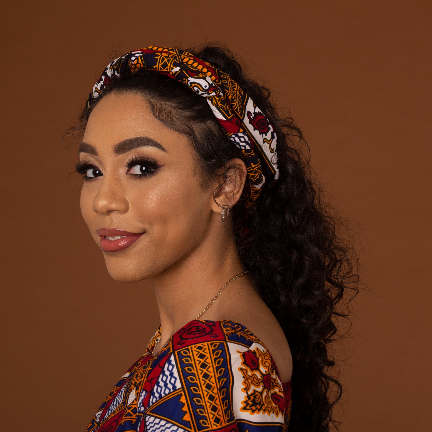 red, yellow, white, and black African print head wrap tied as a turban in floral medallion pattern, made from sustainably sourced Ankara wax print.