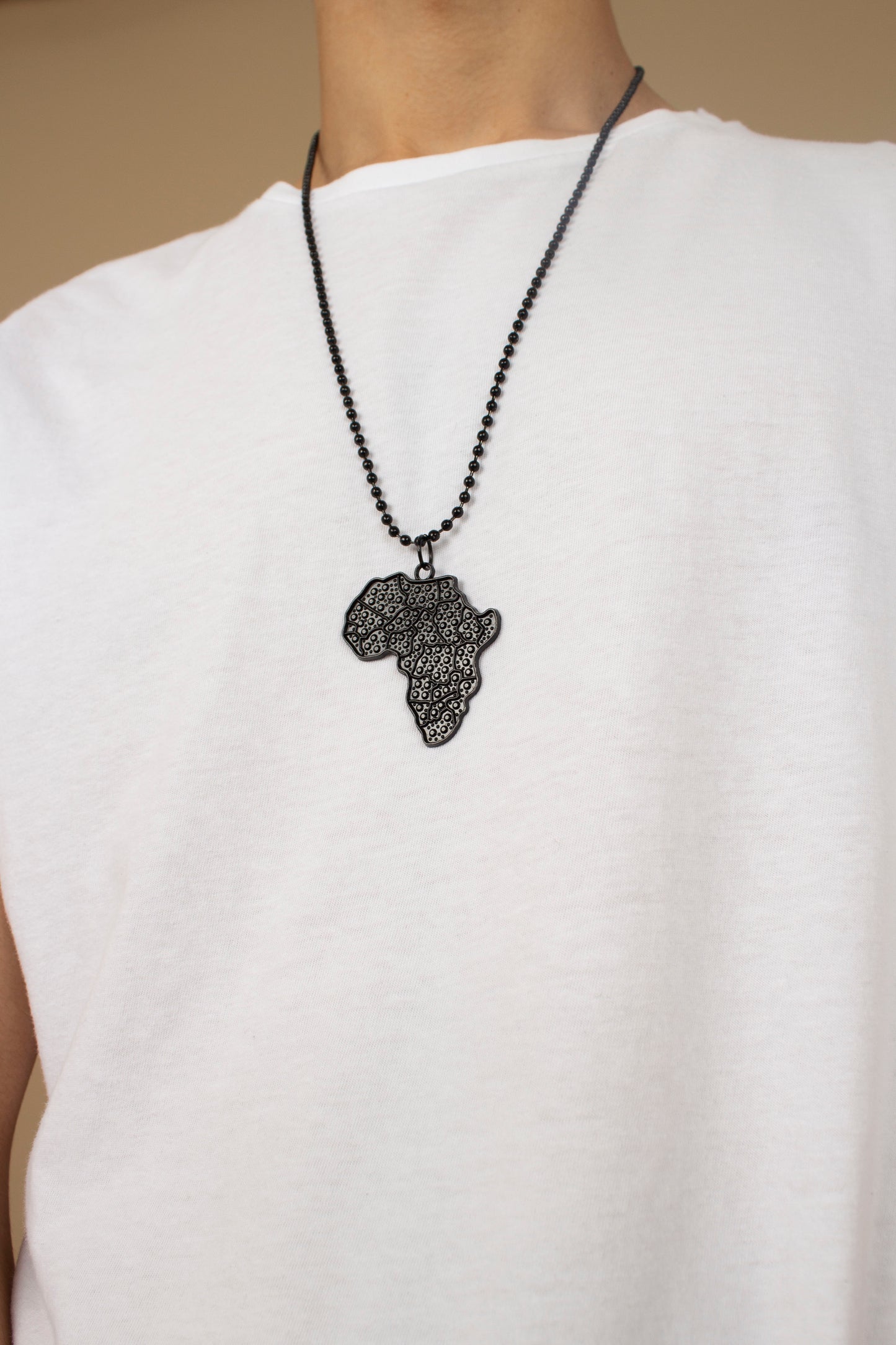 Unisex necklace with a African Map pendant featuring black metallic textured detailing and a metallic chain link. Available in one-size, Designed in England Made in Nigeria.