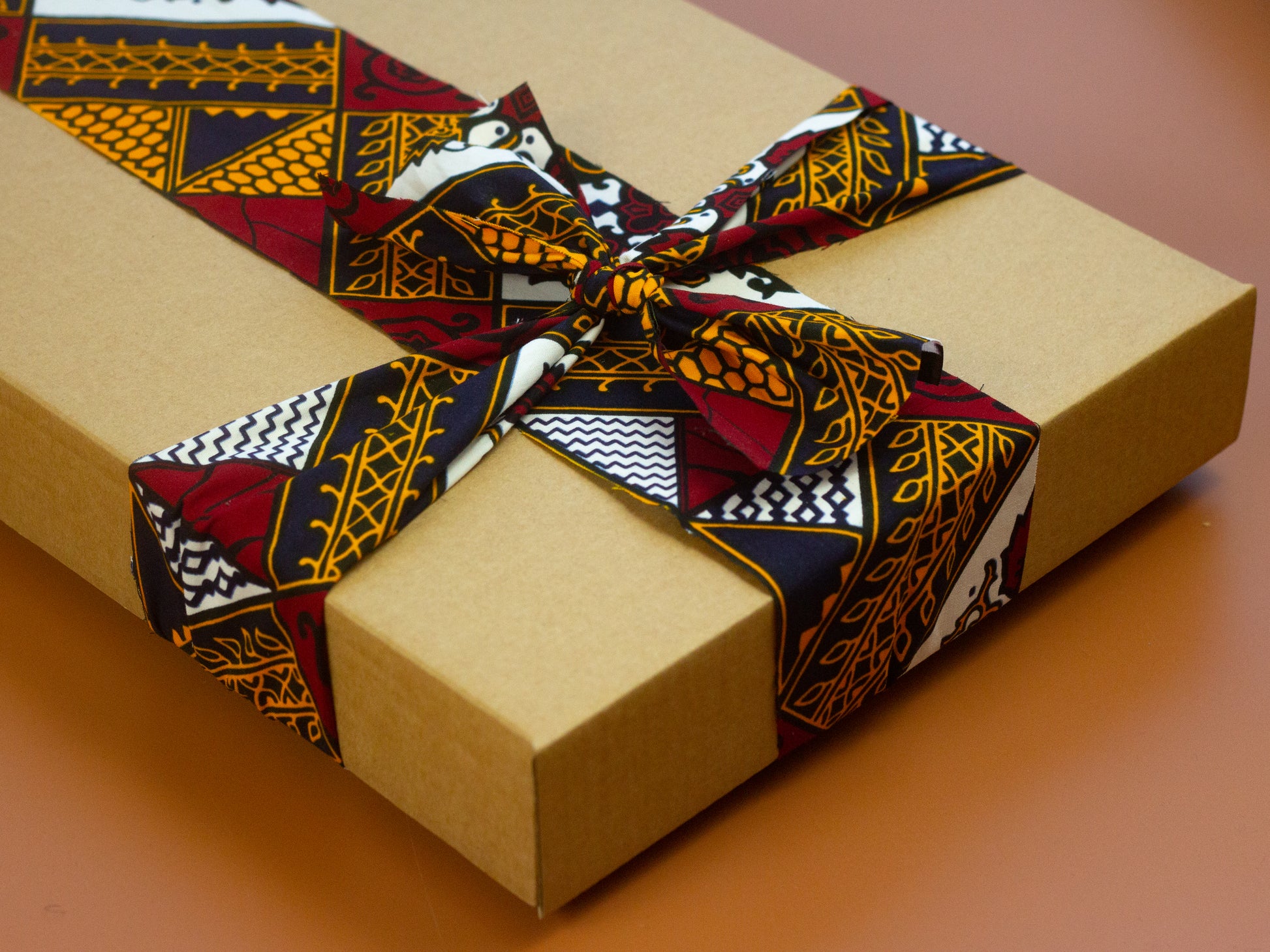 Brown, red, white, and black African print head wrap fabric giftbox display in a floral pattern, made from sustainably sourced Ankara wax print.