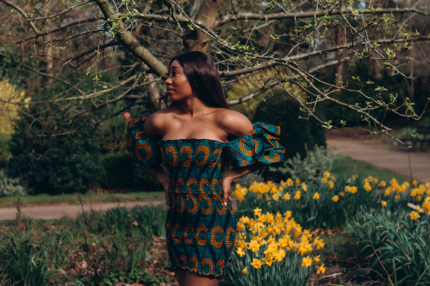 Adetayo African Ankara wax printed fabric in a green, orange and black circle geo-shaped pattern featured Midi-length dress, off-shoulder puff sleeve wit fitted bodice with a fitted elasticated waist reverse and closed back.