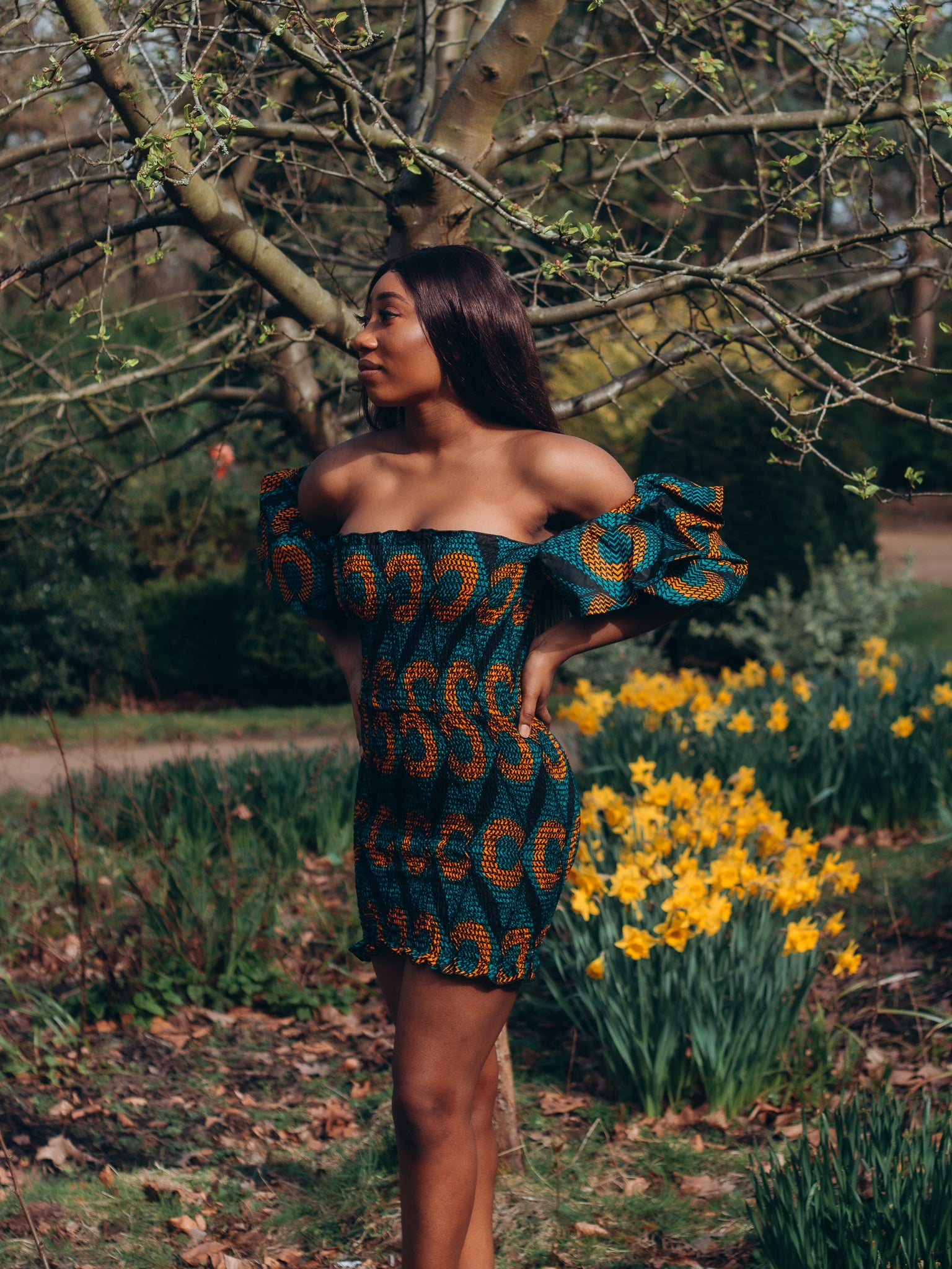 Adetayo African Ankara wax printed fabric in a green, orange and black circle geo-shaped pattern featured Midi-length dress, off-shoulder puff sleeve wit fitted bodice with a fitted elasticated waist reverse and closed back.
