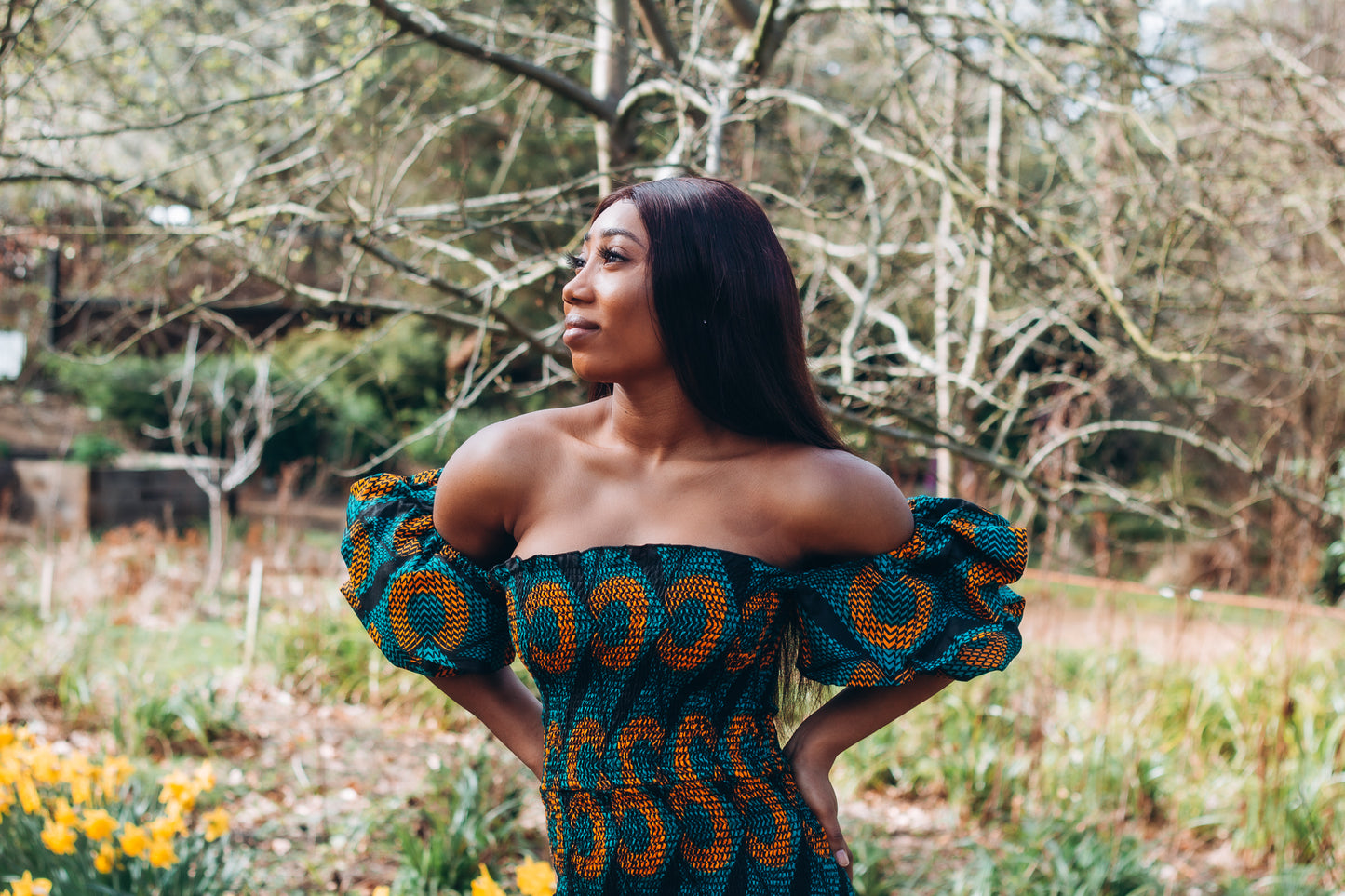Adetayo African Ankara wax printed fabric in a green, orange and black circle geo-shaped pattern featured Midi-length dress, off-shoulder puff sleeve wit fitted bodice with a fitted elasticated waist reverse and closed back.