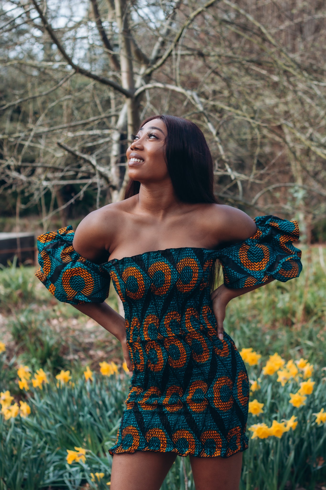 Adetayo African Ankara wax printed fabric in a green, orange and black circle geo-shaped pattern featured Midi-length dress, off-shoulder puff sleeve wit fitted bodice with a fitted elasticated waist reverse and closed back.