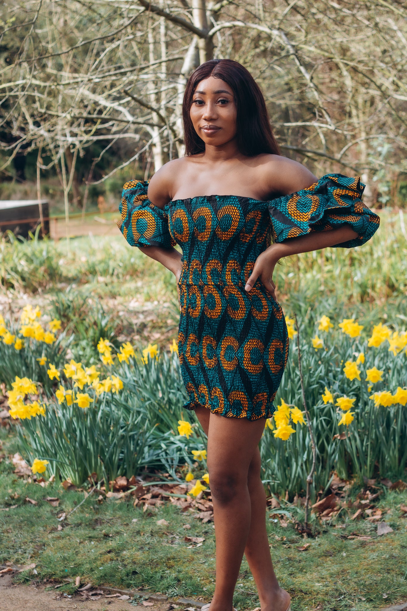 Adetayo African Ankara wax printed fabric in a green, orange and black circle geo-shaped pattern featured Midi-length dress, off-shoulder puff sleeve wit fitted bodice with a fitted elasticated waist reverse and closed back.