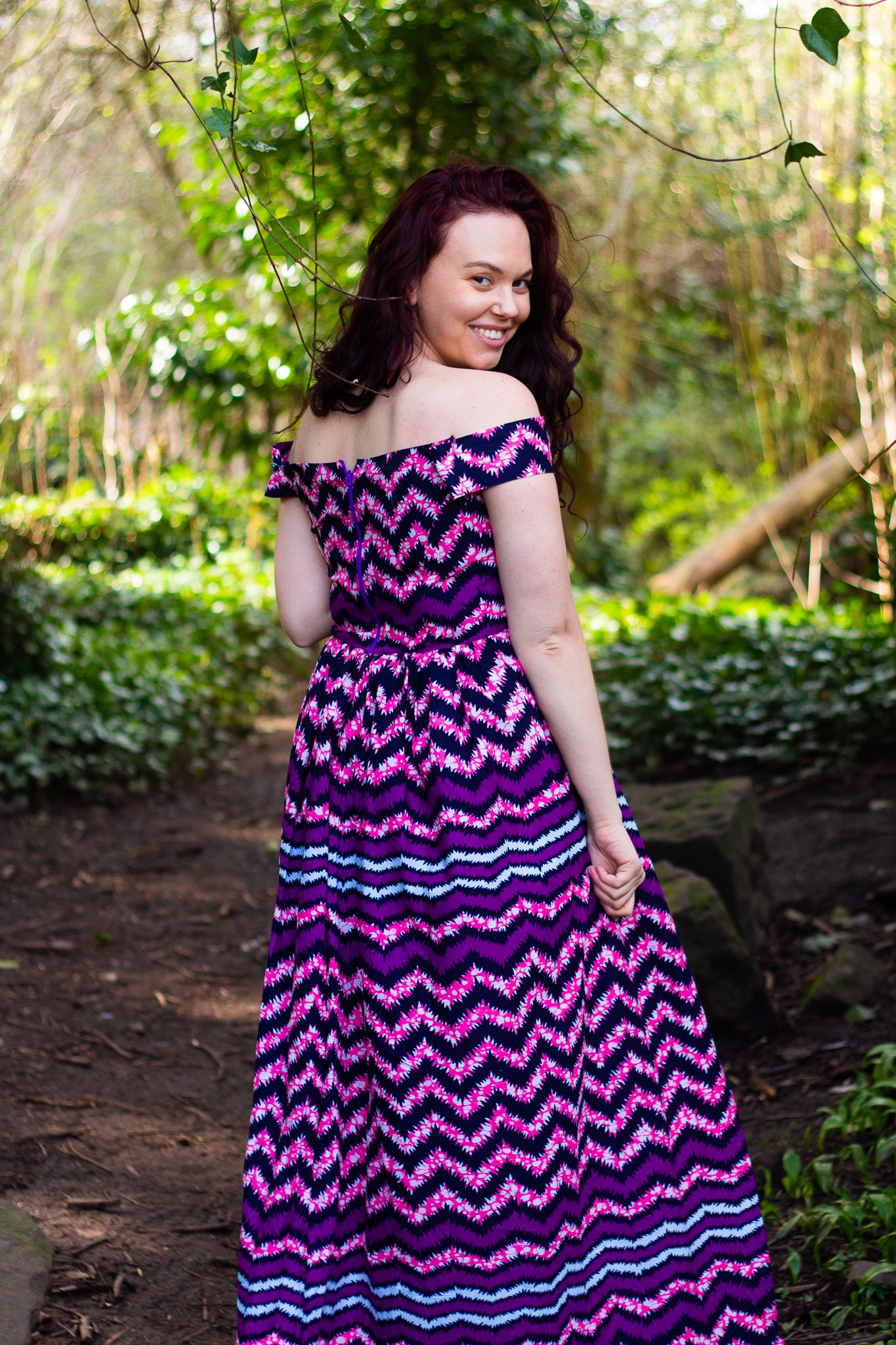  Purple and black African zig-zag texture over-laying a lilac, blue and whites spotted-mesh Ankara wax print on a floor length, short off the shoulder sleeved skater skirt, maxi dress with a thigh high slit.