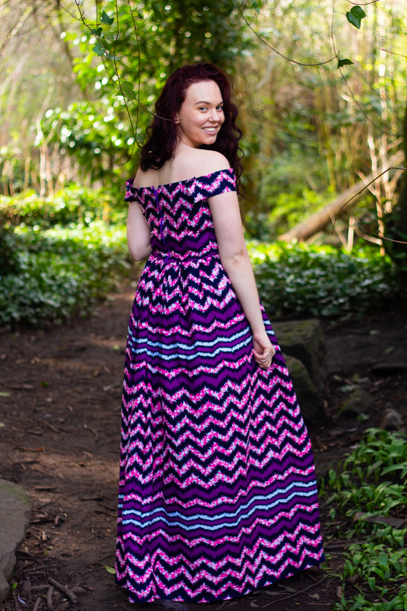  Purple and black African zig-zag texture over-laying a lilac, blue and whites spotted-mesh Ankara wax print on a floor length, short off the shoulder sleeved skater skirt, maxi dress with a thigh high slit.