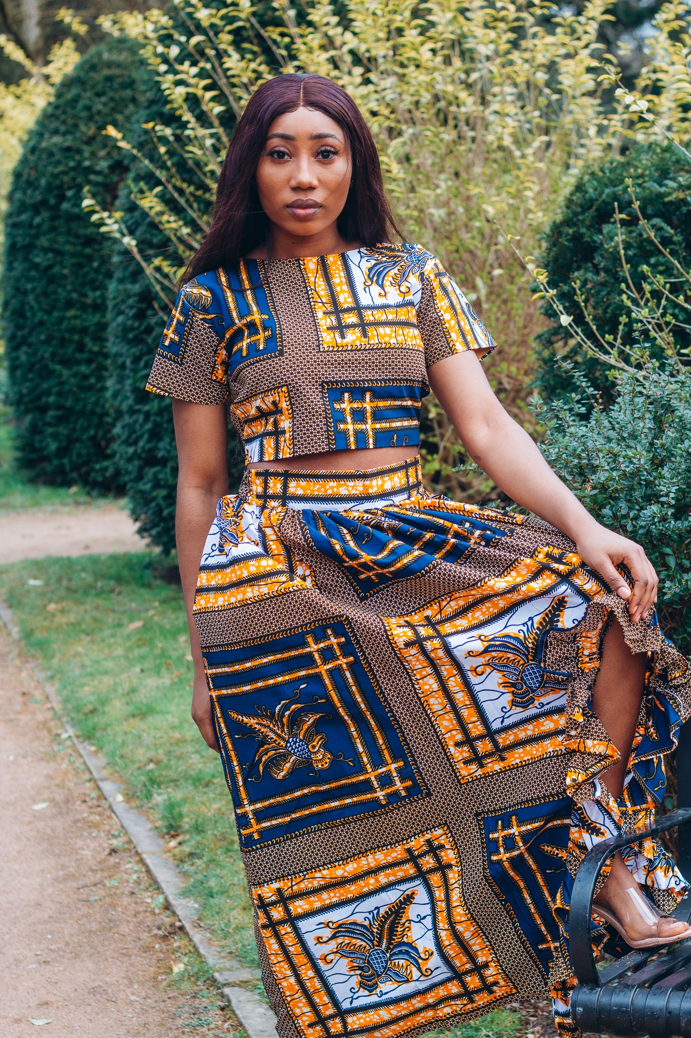 yellow, white, and black Ankara wax print In African floral medallion pattern floor length high to low maxi skirt with a thigh high slit with ruffle detailed and seamed belt made from sustainably sourced Ankara wax print.