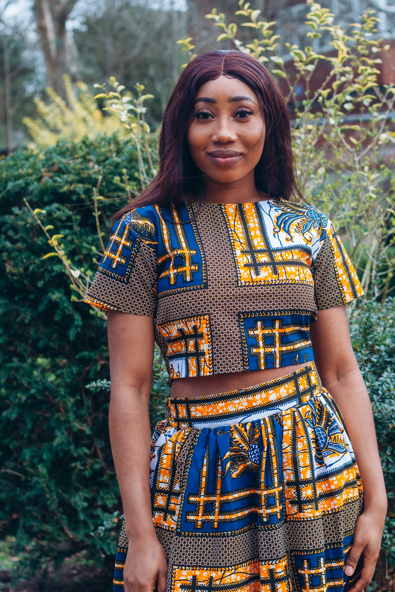 yellow, white, and black Ankara wax print In African floral medallion pattern floor length high to low maxi skirt with a thigh high slit with ruffle detailed and seamed belt made from sustainably sourced Ankara wax print.