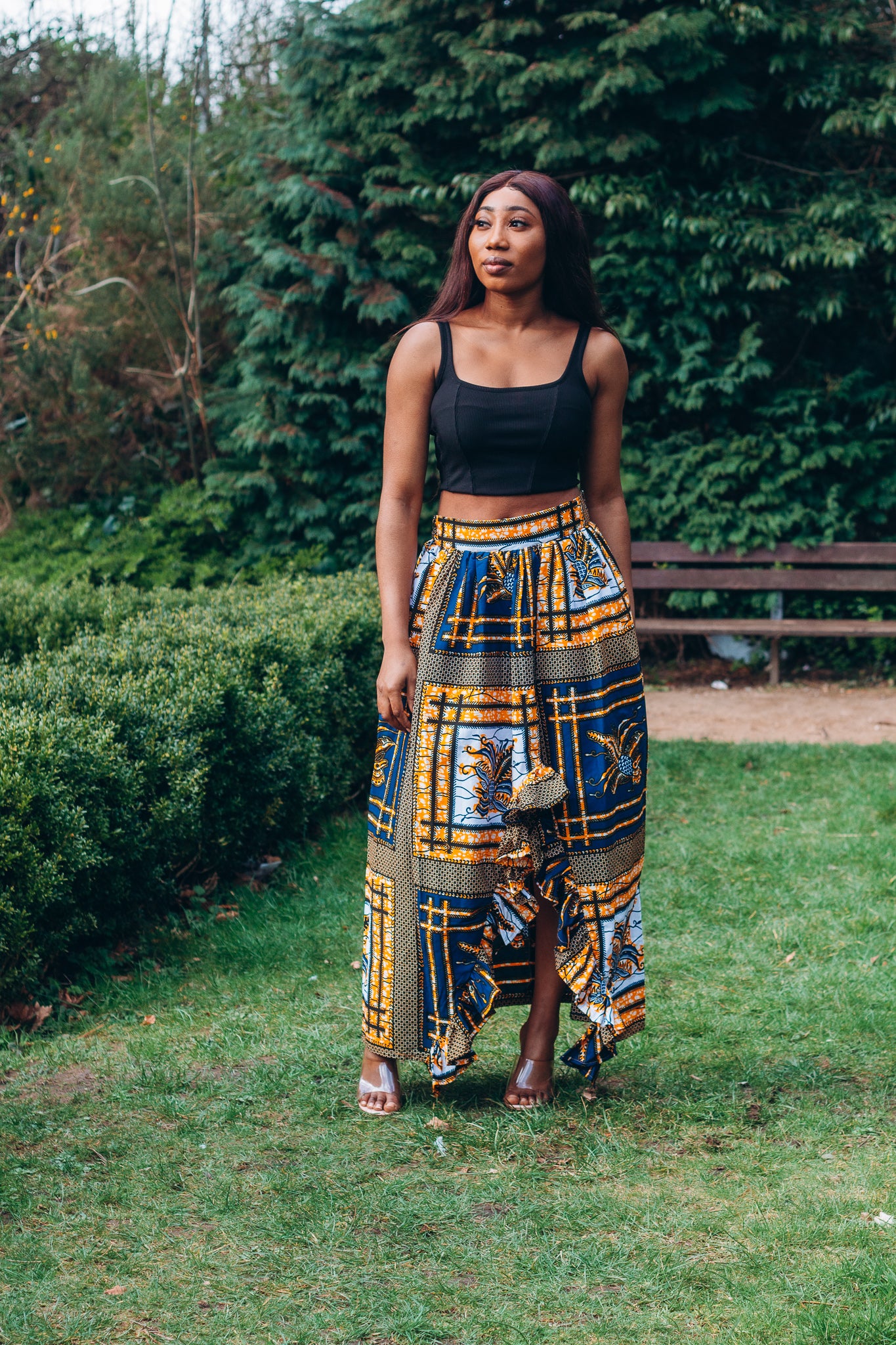 yellow, white, and black Ankara wax print In African floral medallion pattern floor length high to low maxi skirt with a thigh high slit with ruffle detailed and seamed belt made from sustainably sourced Ankara wax print.