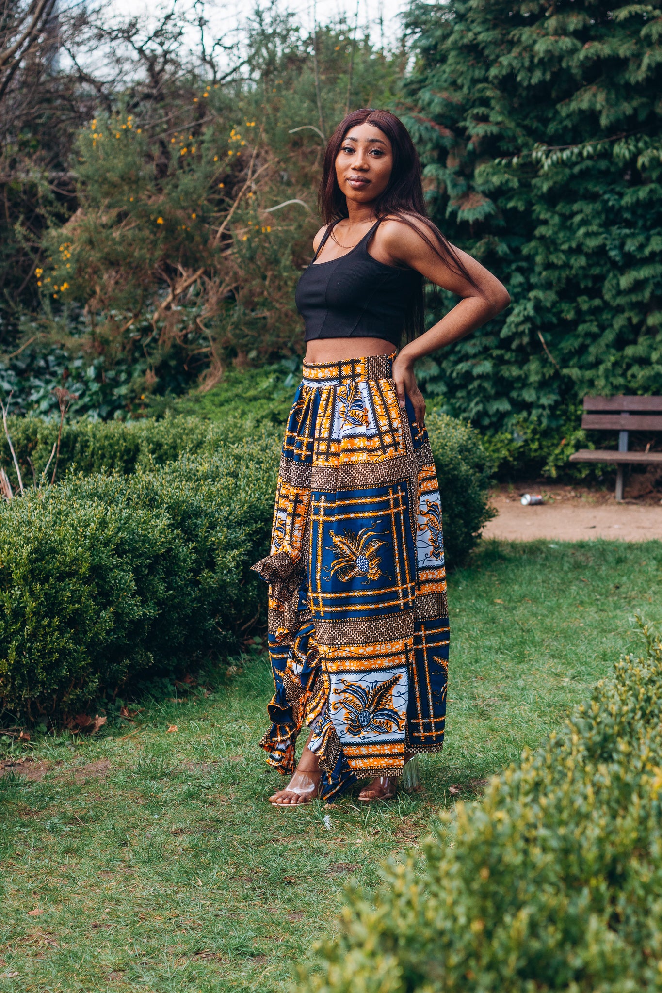 yellow, white, and black Ankara wax print In African floral medallion pattern floor length high to low maxi skirt with a thigh high slit with ruffle detailed and seamed belt made from sustainably sourced Ankara wax print.