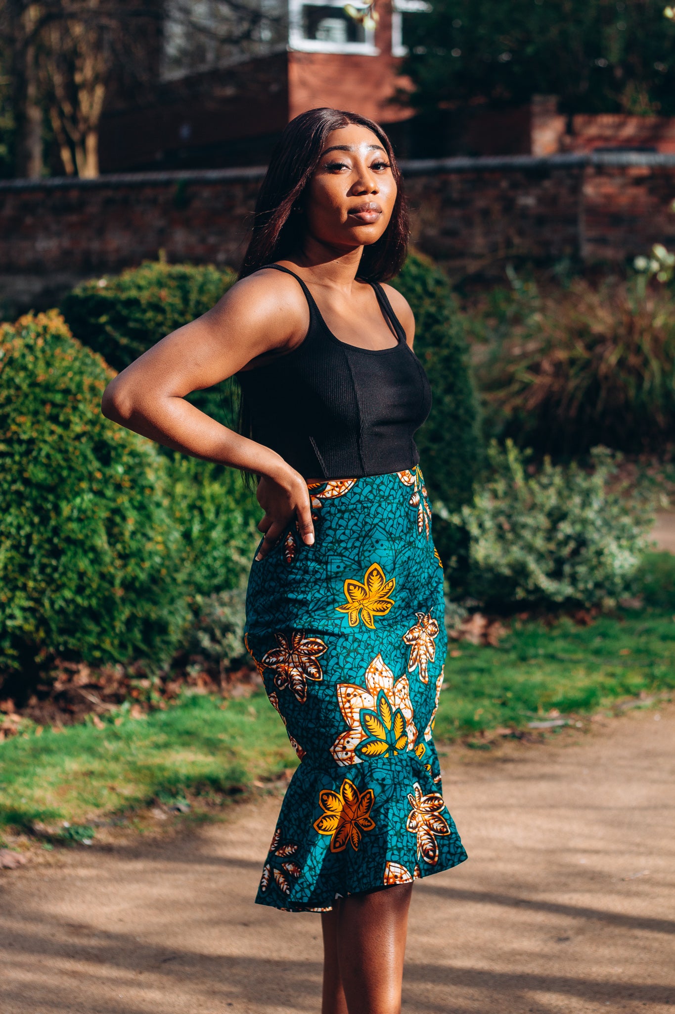 Orange, yellow, white and green African print High Waisted knee length Flared fishtail Skirt with seamed belt detailing in a floral pattern, made from sustainably sourced Ankara wax print..
